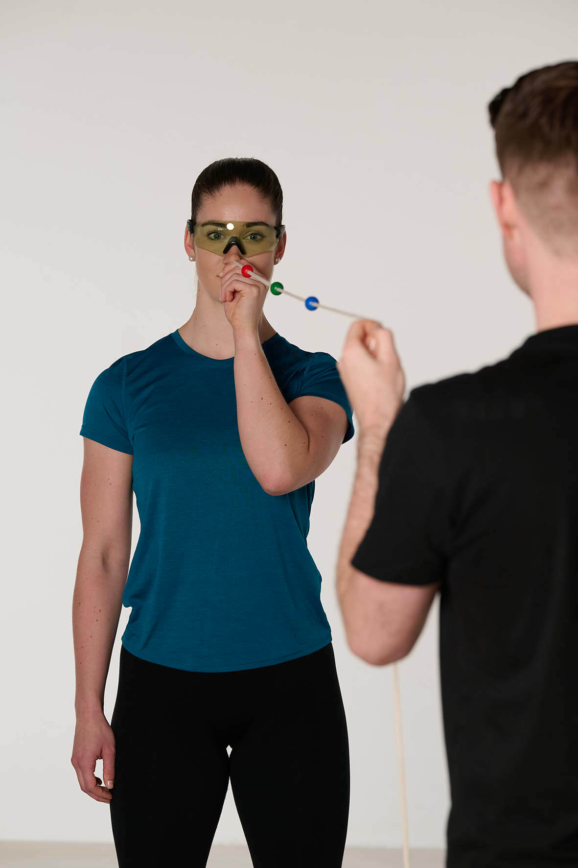 Frau mit Brille hält eine Schnur mit Kugeln vor ihr Gesicht, Kevin Grafen steht unscharf im Vordergrund und hält die Schnur