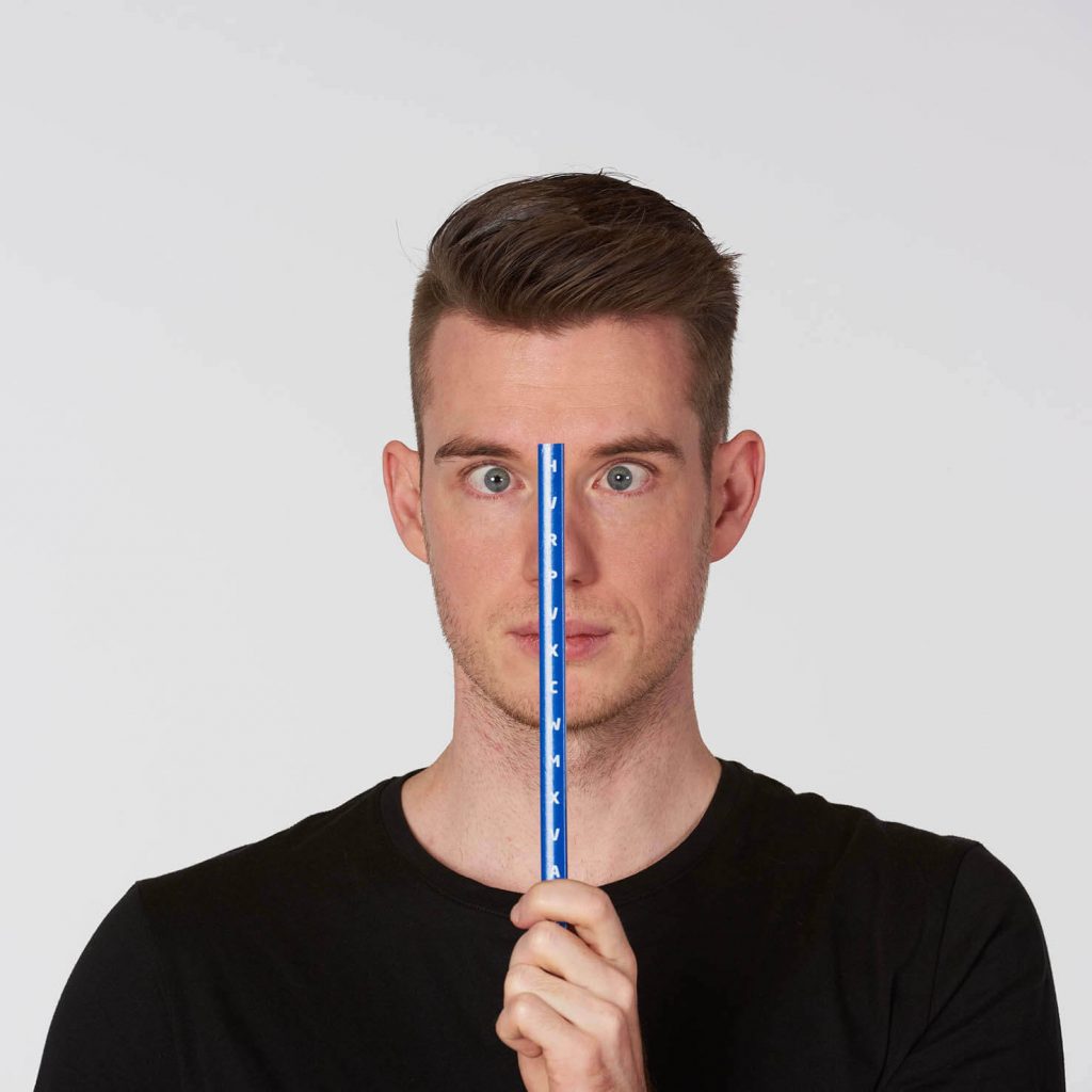 Porträt von Kevin Grafen, der einen Stab mit Buchstaben vor sein Gesicht hält und schielt